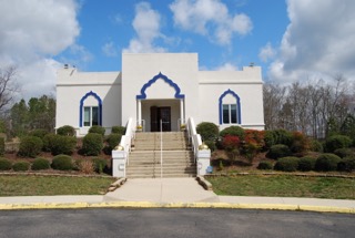 The front entrance of the Richmond Sikh Gurdwara, white with blue cusped arches
