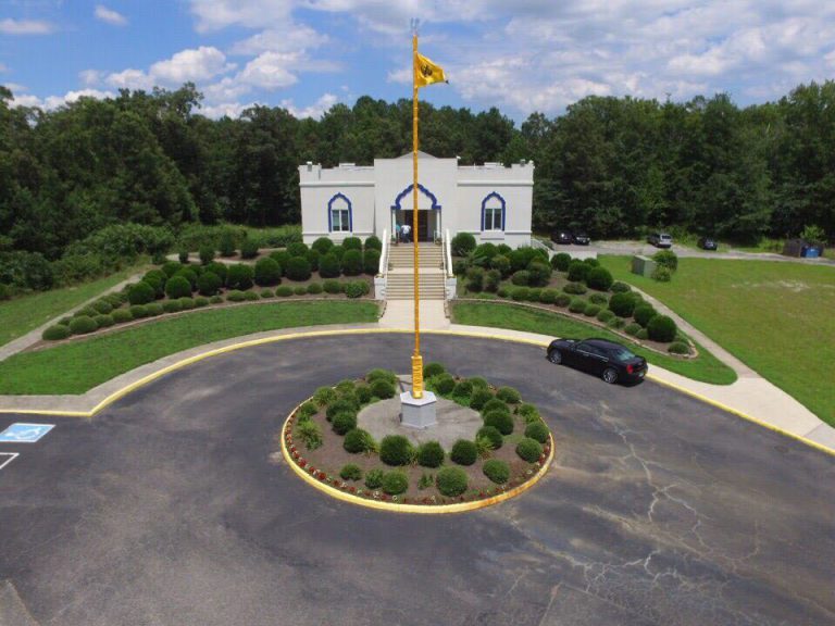 The Richmond Sikh Gurdwara — a white building with blue arches, the saffron Nishan Sahib flying before it